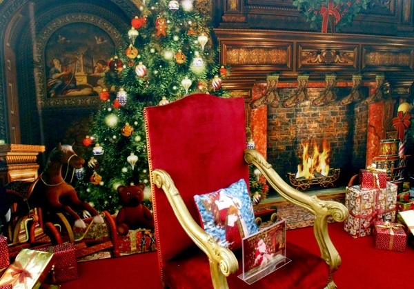 Roter Thronsessel mit Goldarmlehnen vor Hintergrundbild mit Weihnachtsbaum und Kamin, Schaukelpferd und Geschenke seitlich